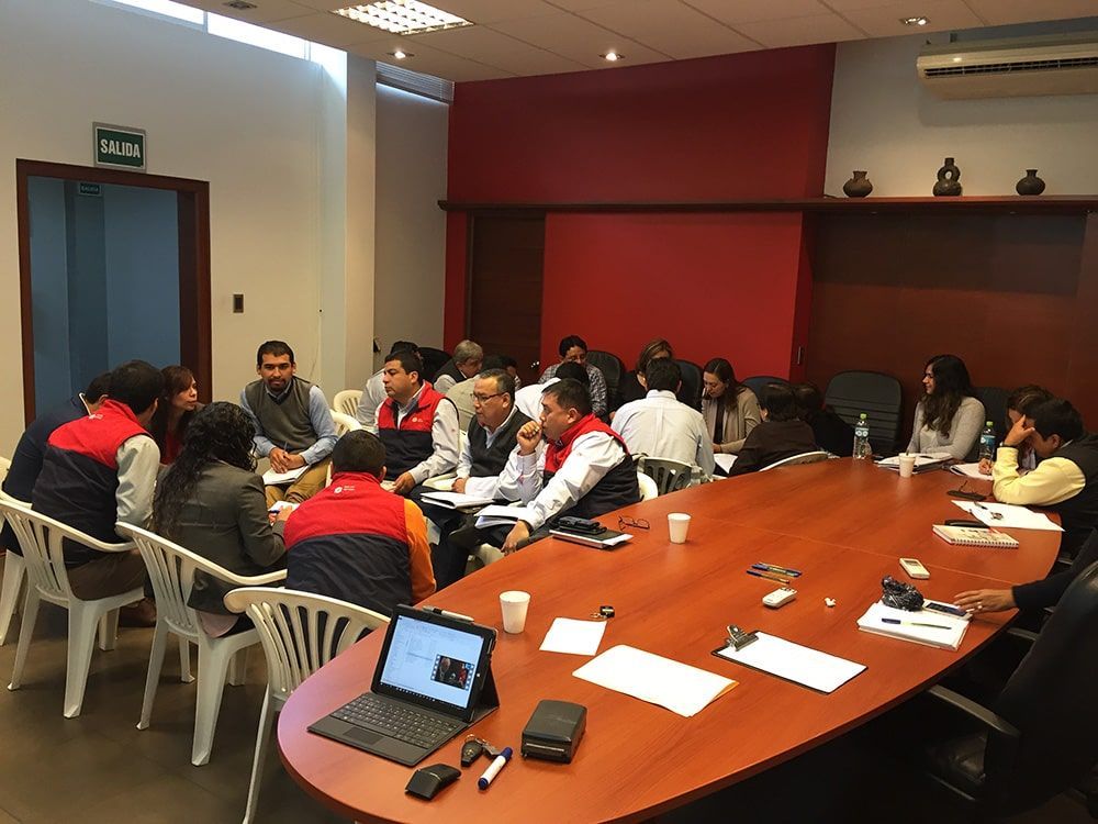 Un grupo de personas está sentado alrededor de una mesa larga en una sala de conferencias.