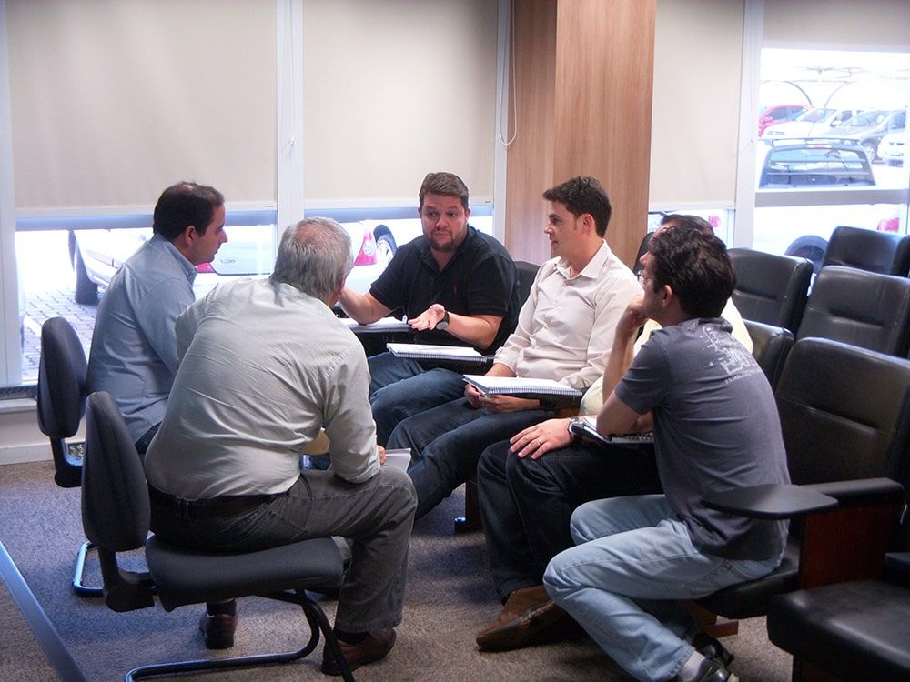 Un grupo de hombres están sentados alrededor de una mesa hablando entre ellos.
