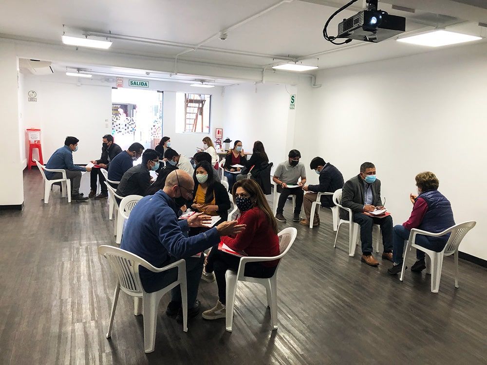 Un grupo de personas con máscaras están sentadas en mesas en una habitación.