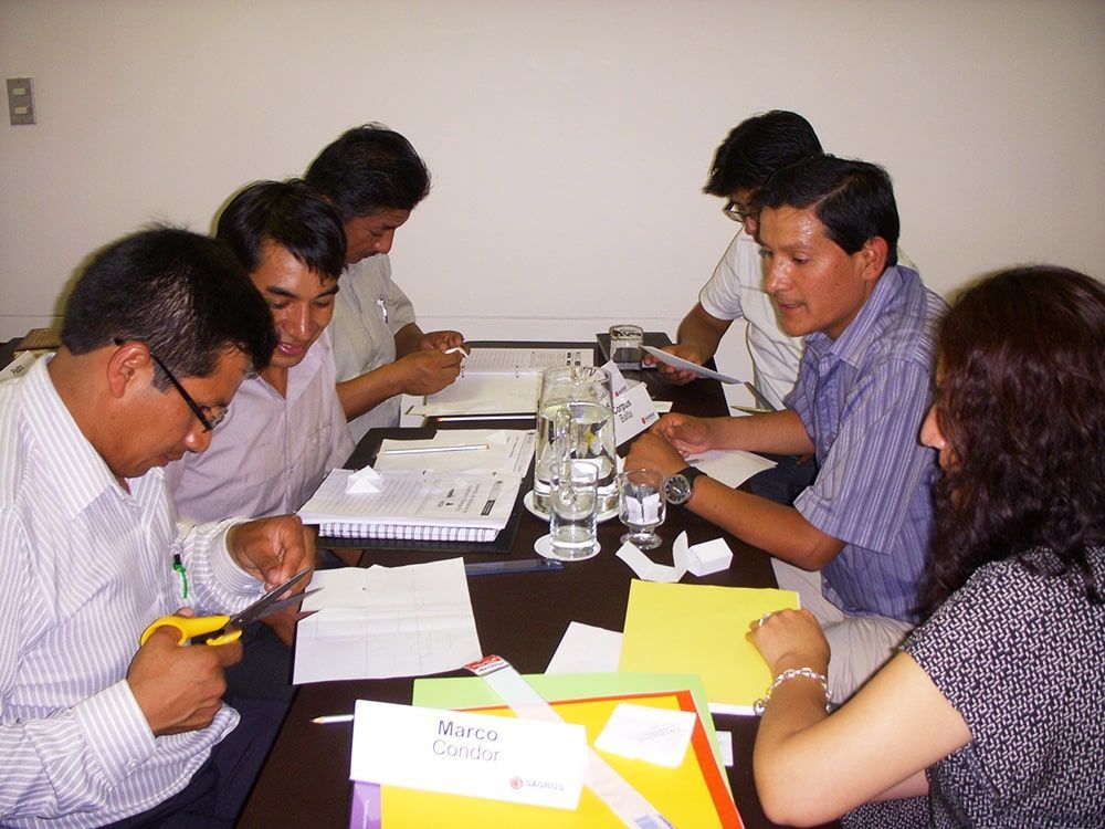 Un grupo de personas se sientan alrededor de una mesa con una etiqueta que dice Marco.