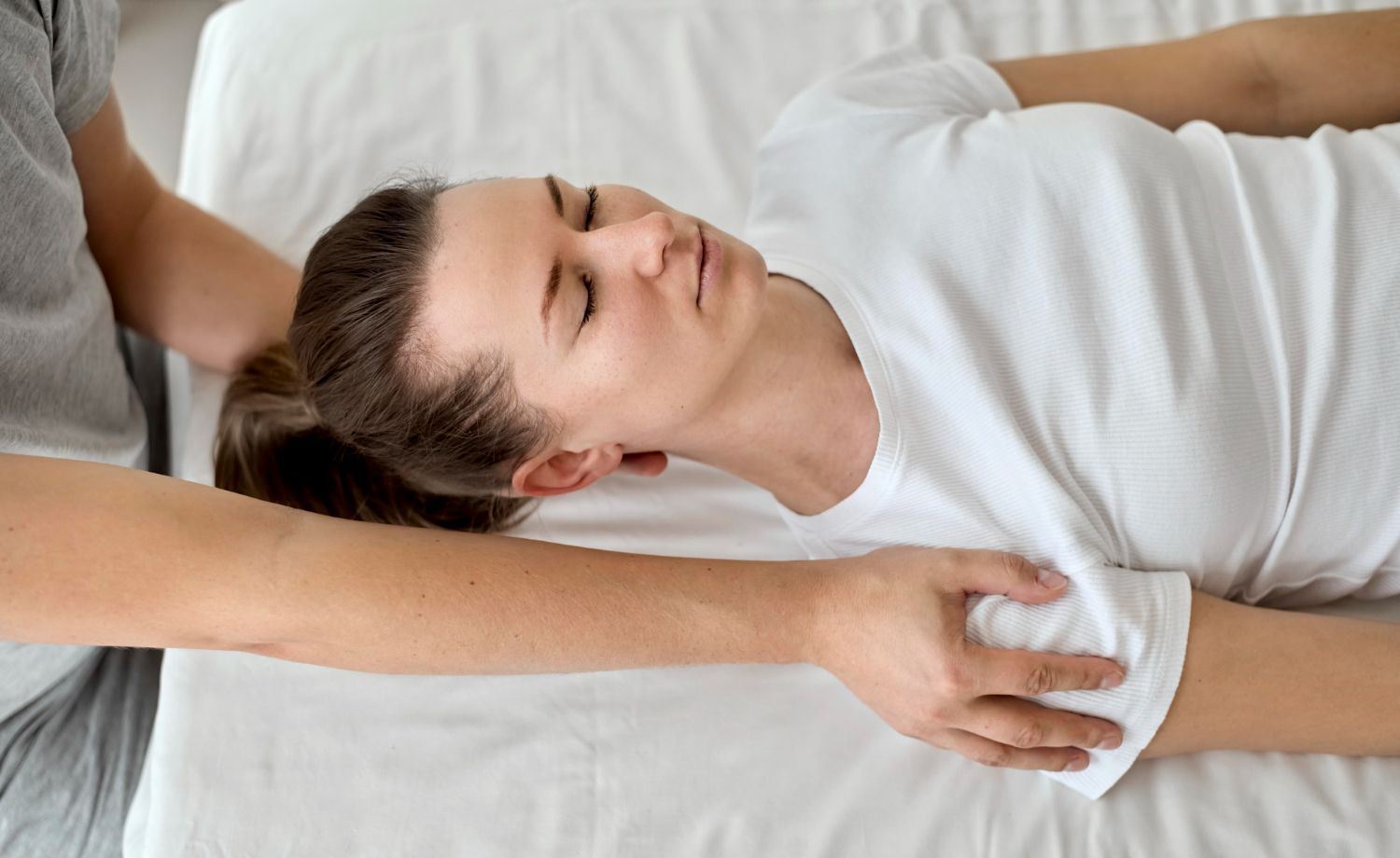 A woman is laying on a bed getting a massage from a man.