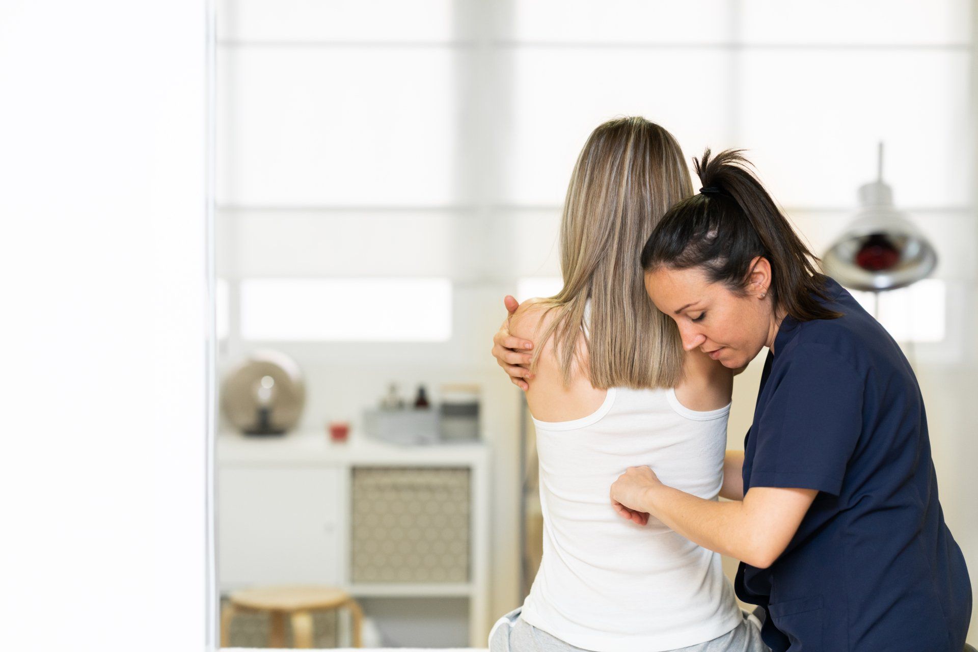 A woman is getting a massage from a nurse in a room.