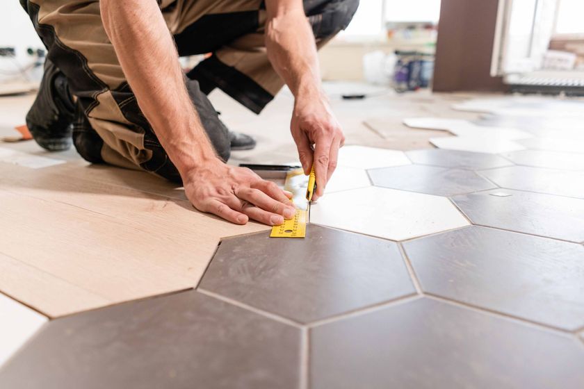 a man is kneeling on the floor while applying glue to a tile floor