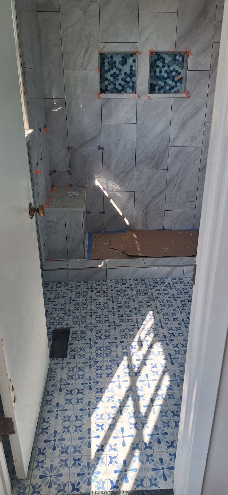 Accessible modern shower with grab bars, built-in bench, and heated towel rack. Light gray tile.