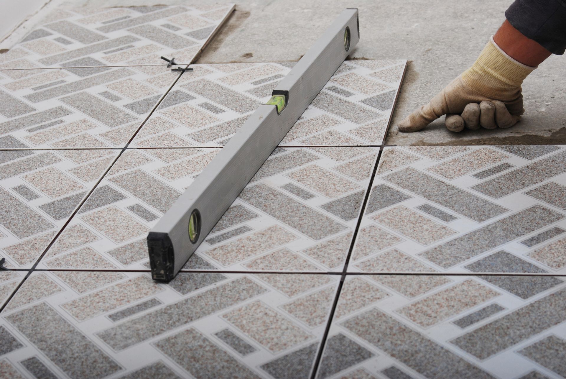Tiled floor being installed; a level is used to check the height of the tiles.