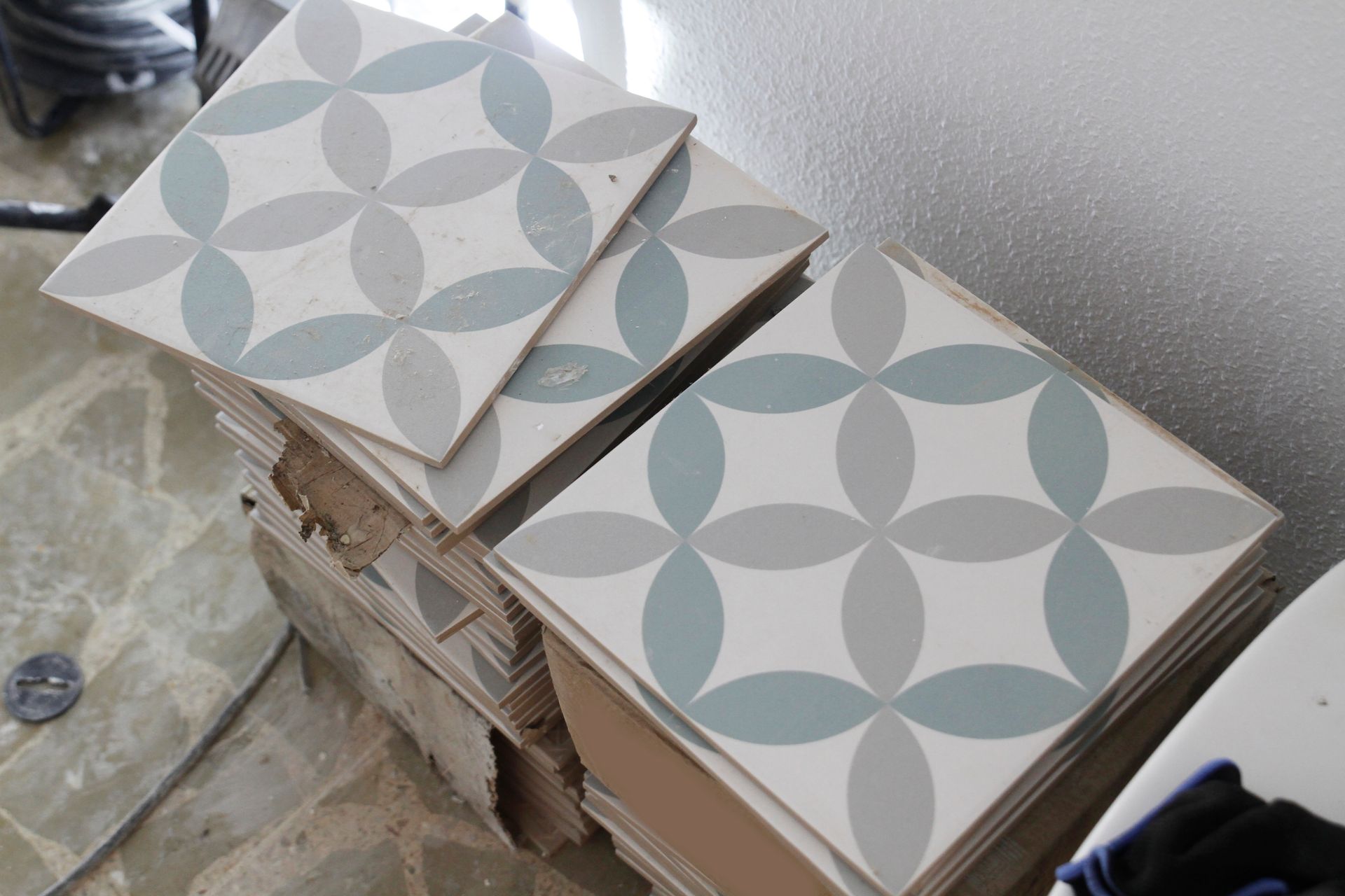 Stack of patterned square tiles with a blue and gray floral design.