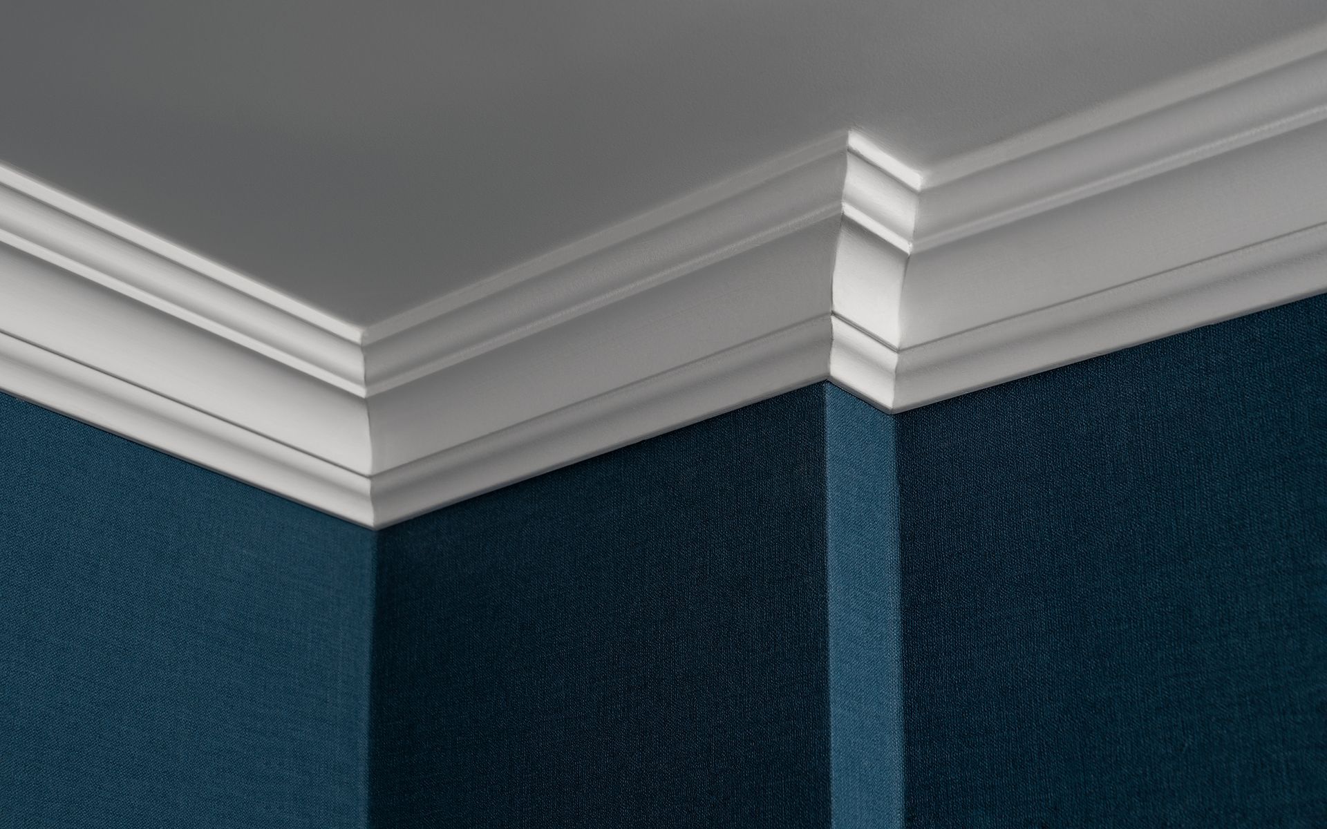 White crown molding at the corner of a room with blue textured walls and a white ceiling.