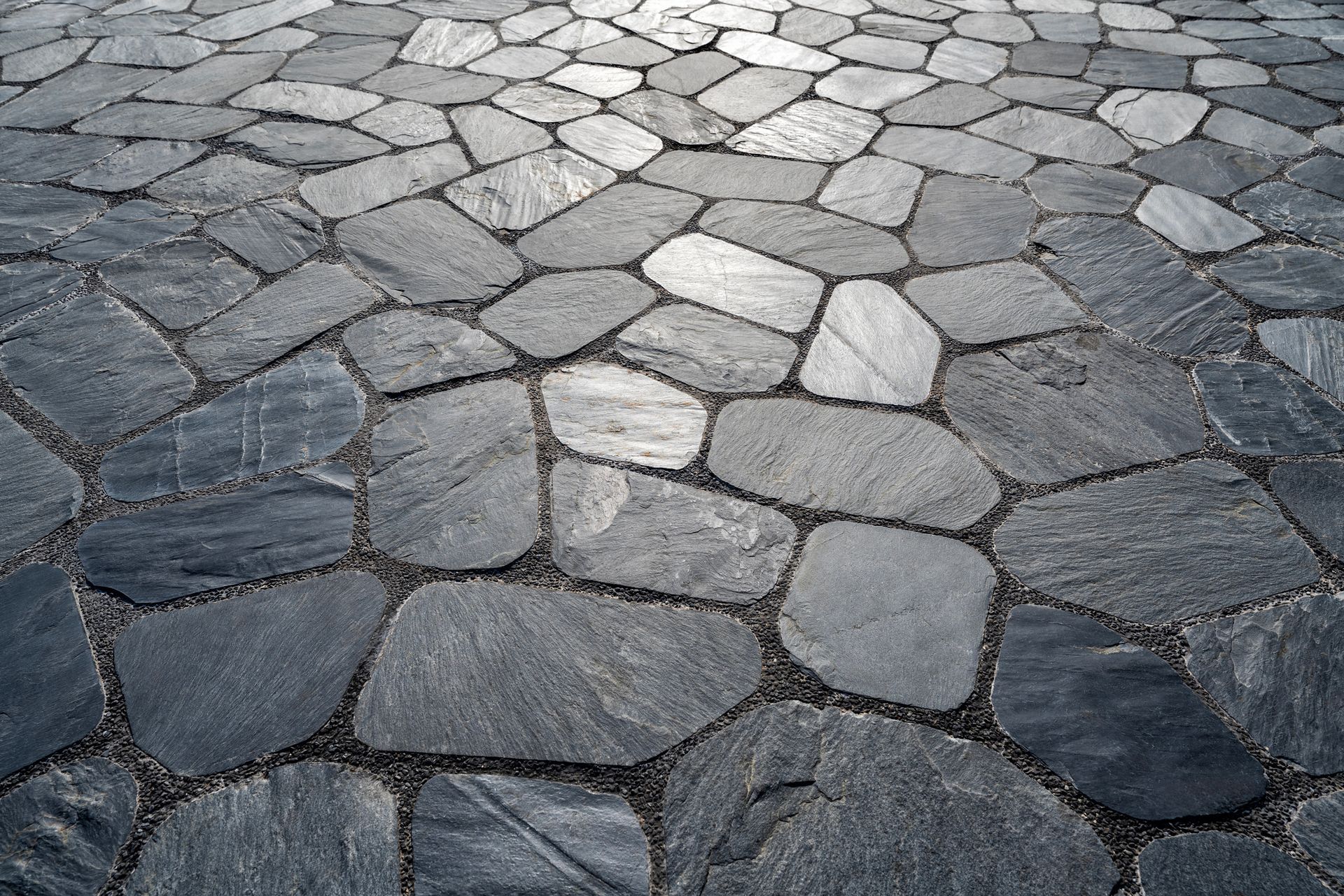 Dark gray stone pavers forming a textured ground surface with contrasting grout.
