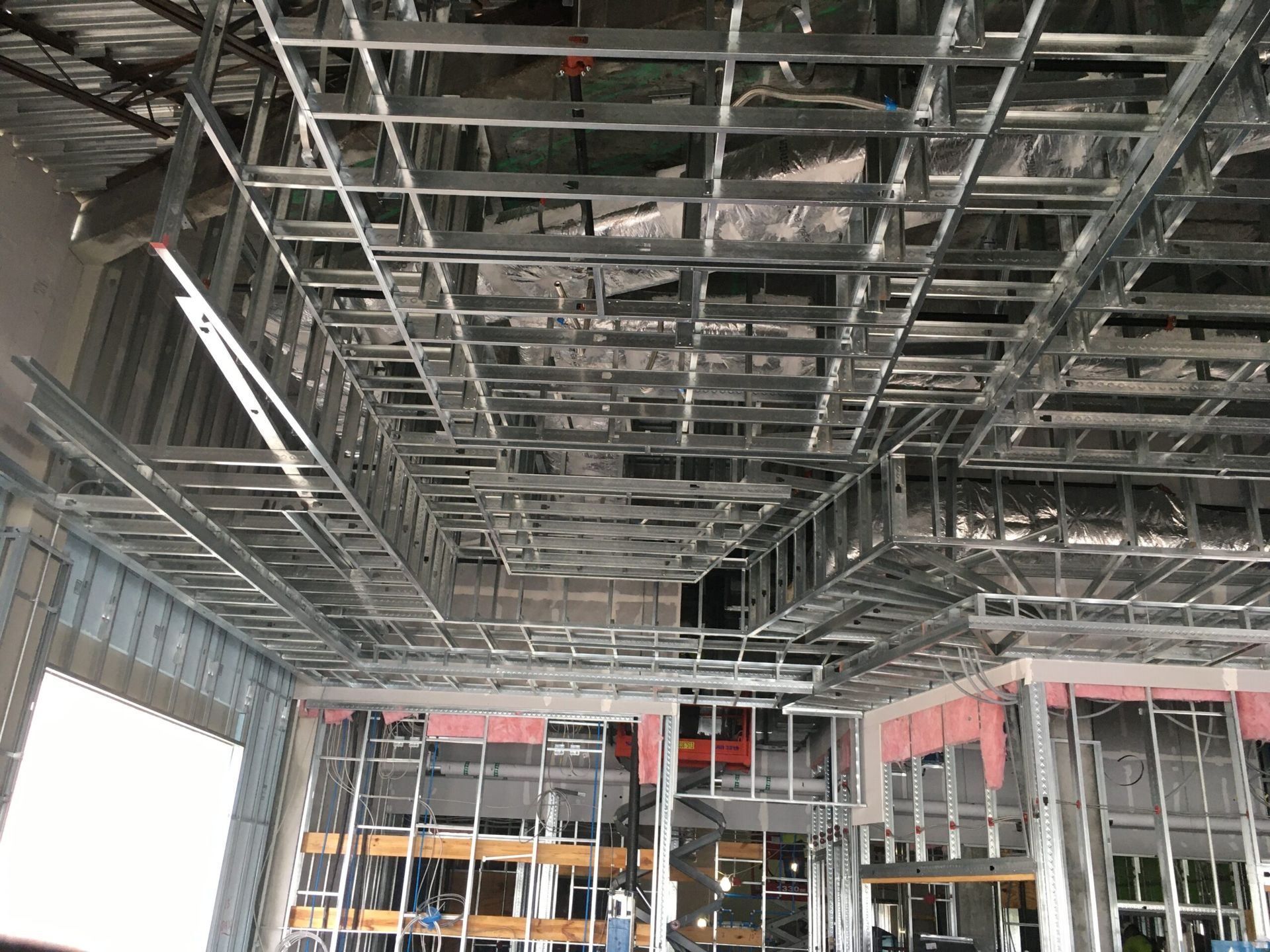 A building under construction with a lot of metal frames hanging from the ceiling.