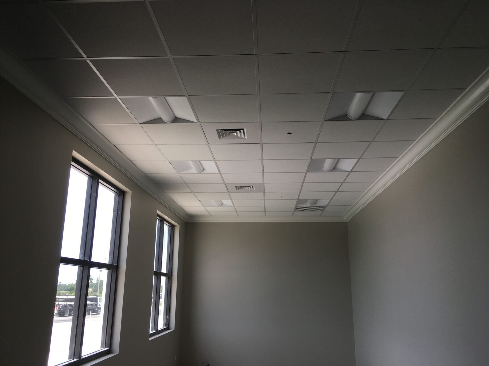 A room with a tiled ceiling and a lot of windows
