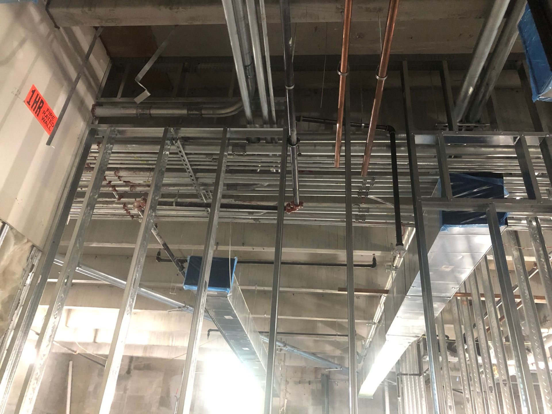 A building under construction with a lot of pipes hanging from the ceiling.