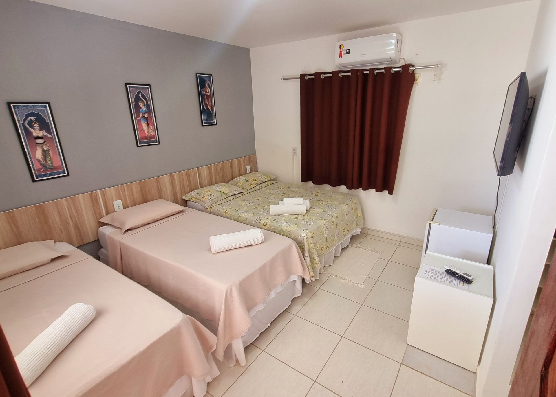 Um quarto de hotel com três camas e uma televisão Pousada Cantinho da Melão