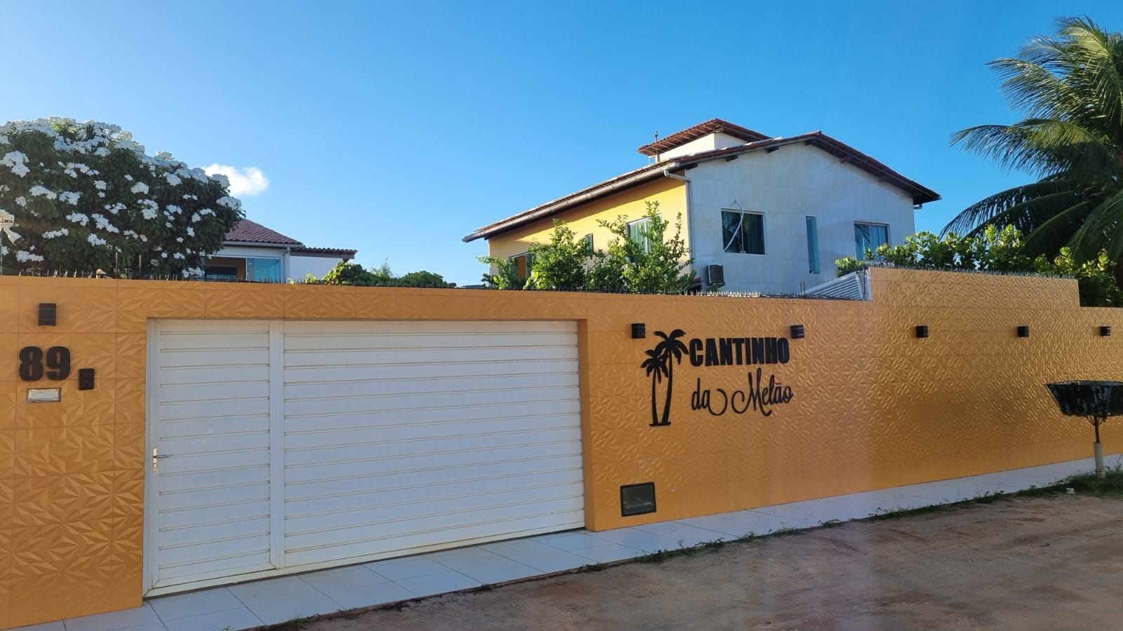 Um prédio amarelo com uma rede na frente Pousada Cantinho da Melão