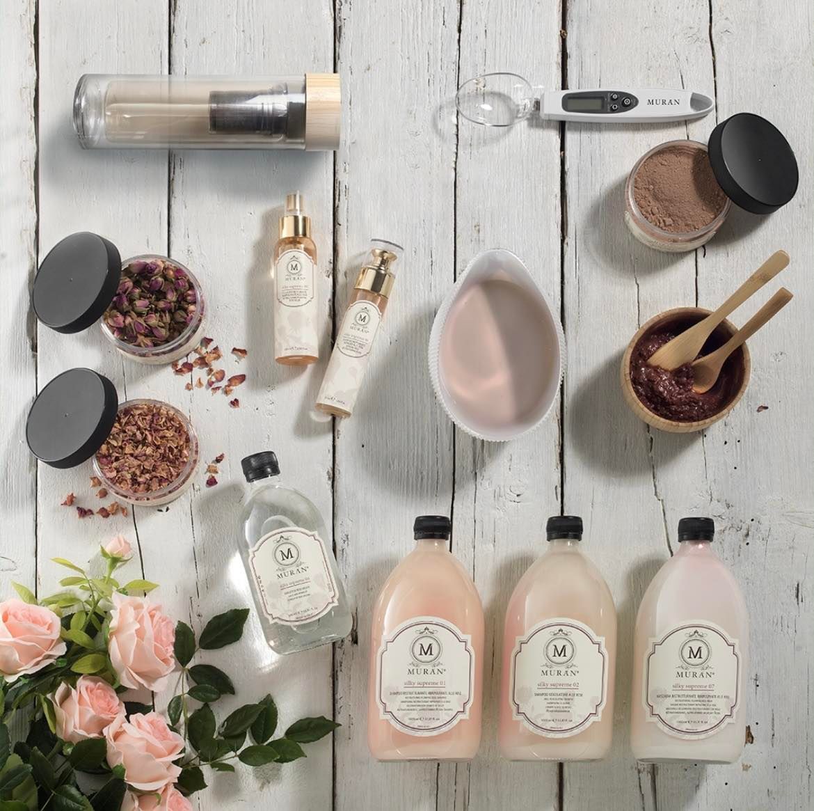 Un tavolo di legno bianco sormontato da bottiglie e fiori