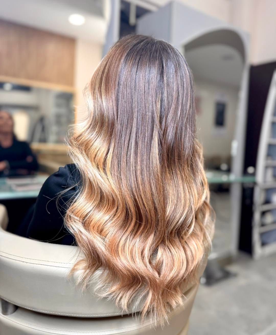 Una donna con i capelli lunghi è seduta su una sedia in un salone.