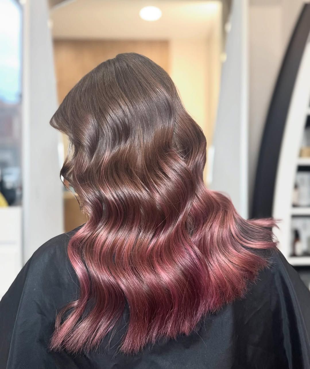 Una donna con lunghi capelli ondulati è seduta su una sedia in un salone.