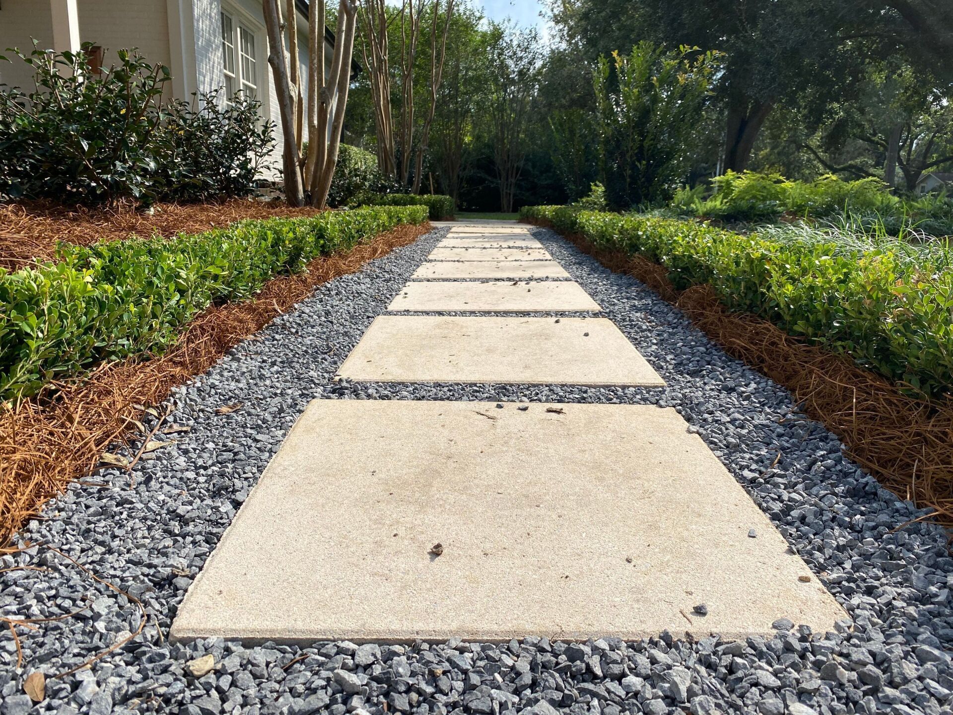 A walkway with gravel and concrete slabs leading to a house