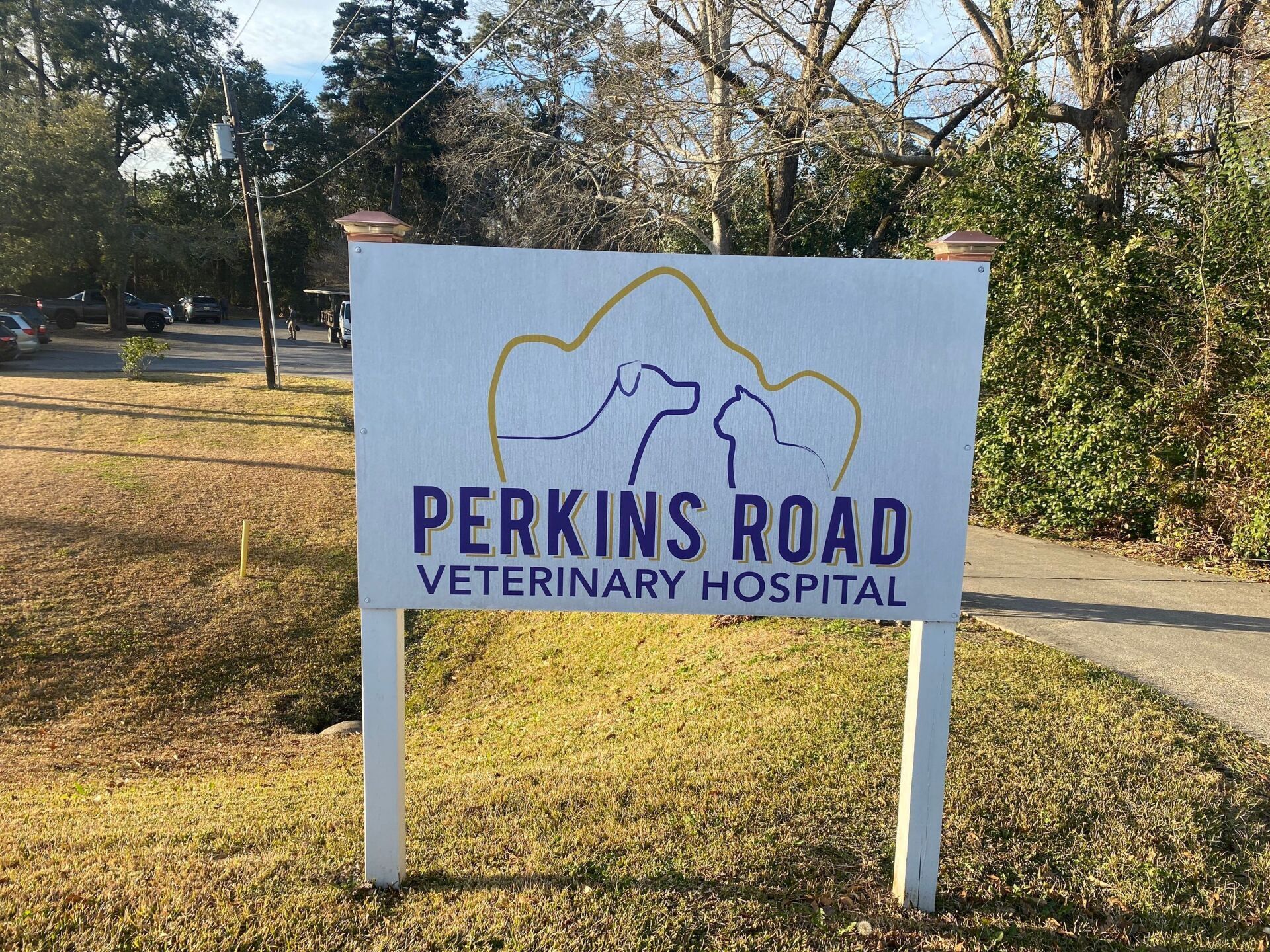 A sign for perkins road veterinary hospital is sitting in the grass.
