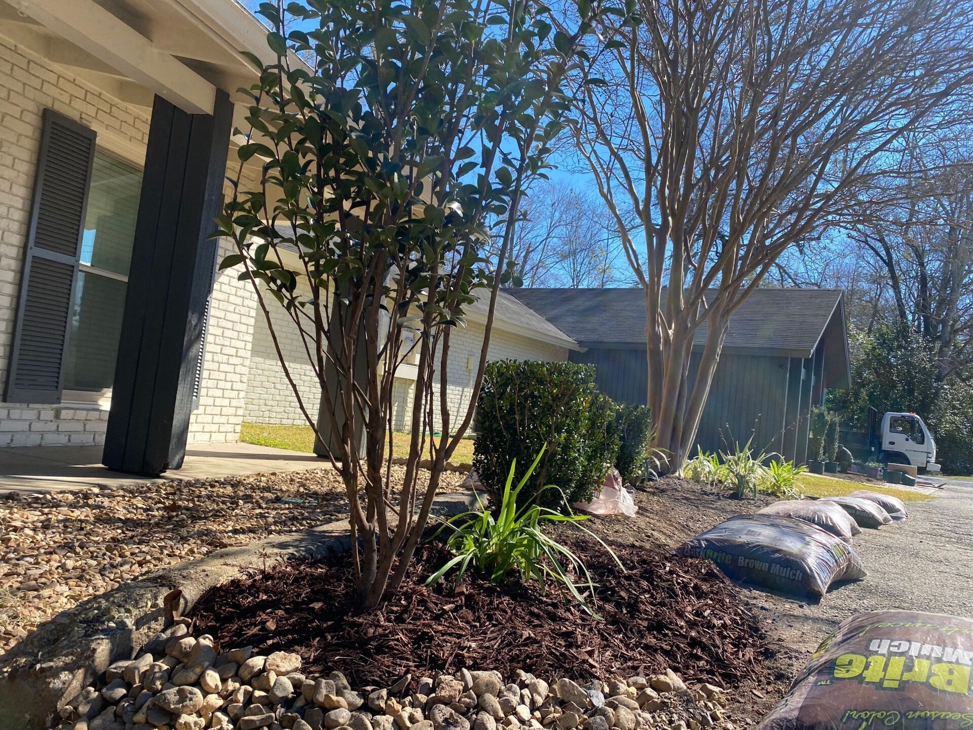 A pile of mulch is sitting in front of a house.