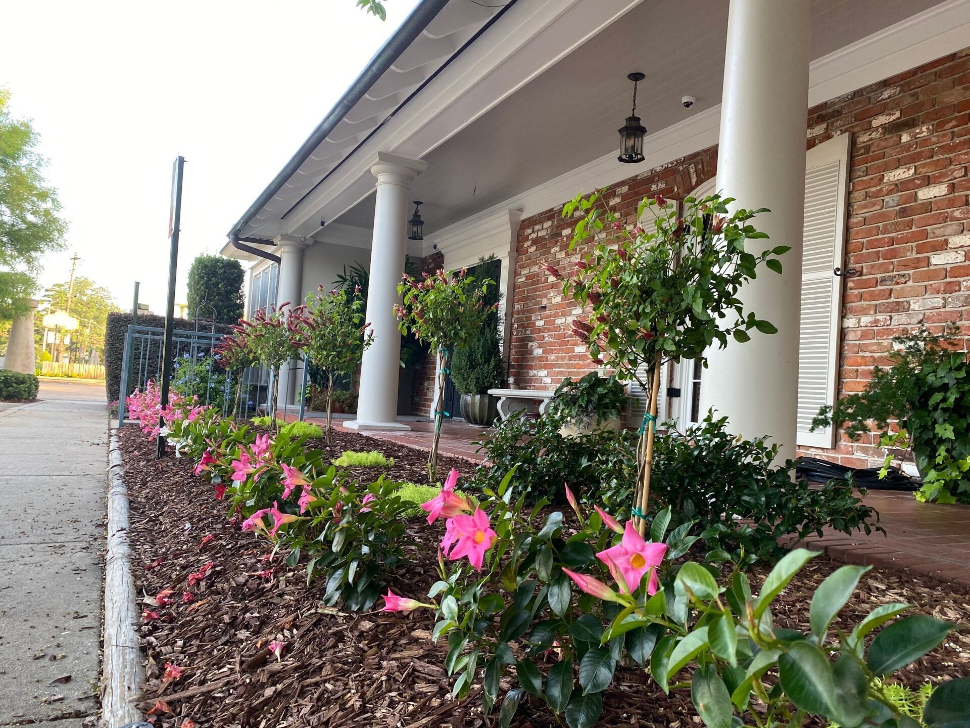 A brick house with pink flowers in front of it