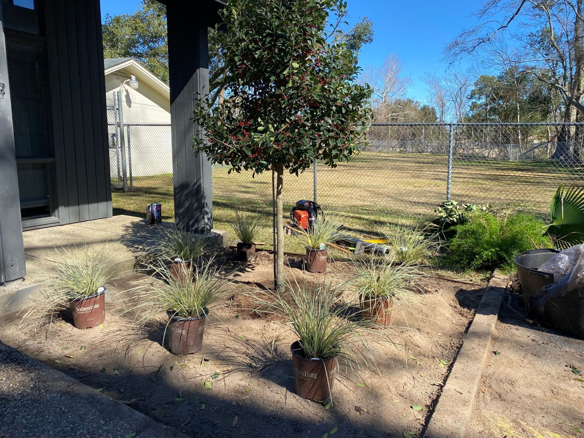 A bunch of potted plants are sitting in the dirt in front of a house.