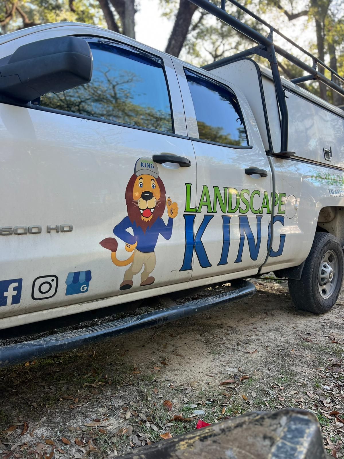 A white truck with a lion on the side is parked in the dirt.