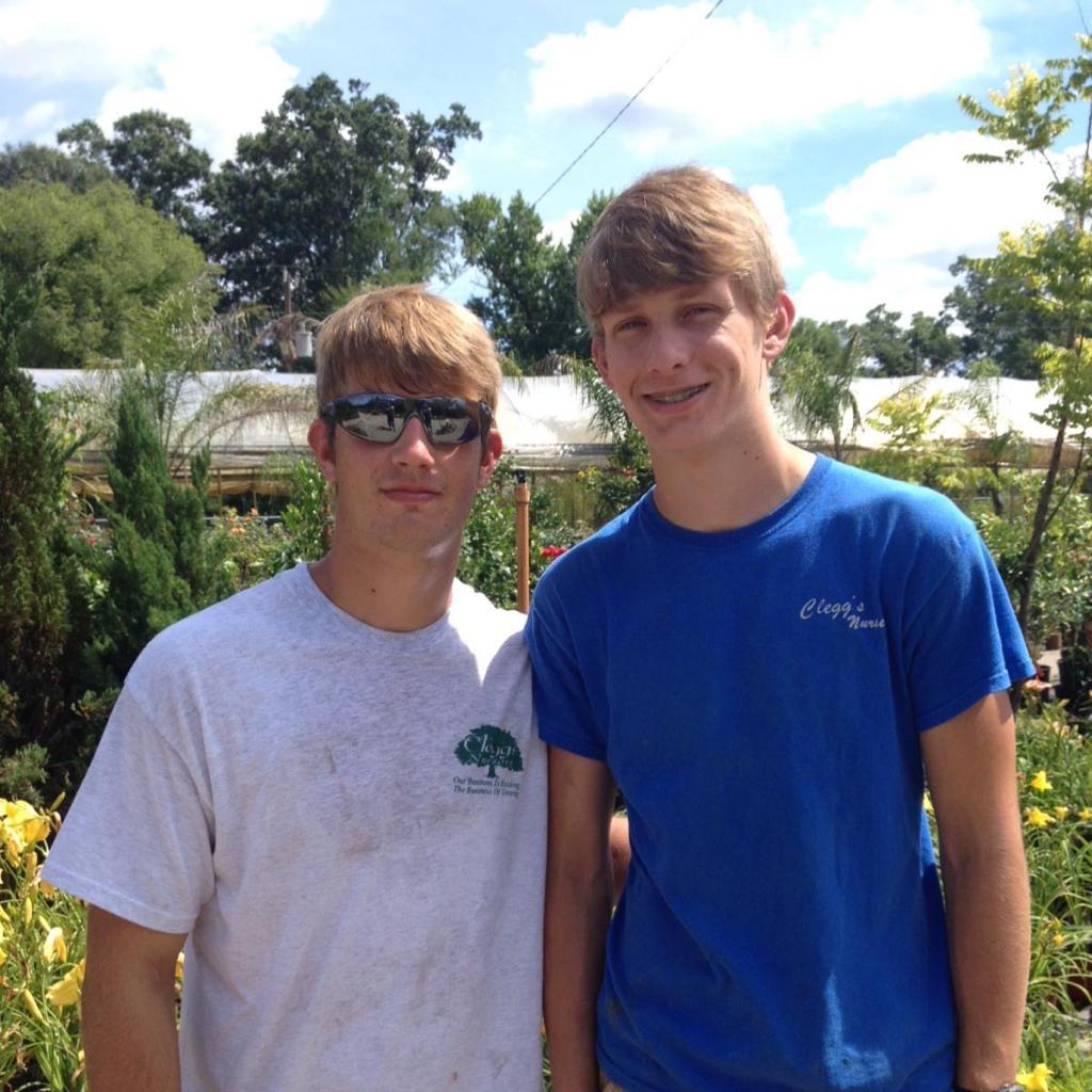 Two young men posing for a picture with one wearing a white shirt with a tree on it