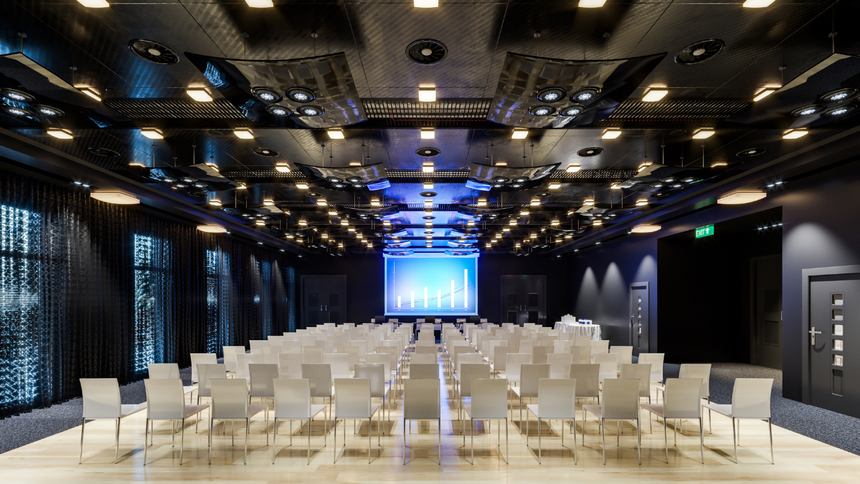 A large conference room with rows of chairs and a large screen.