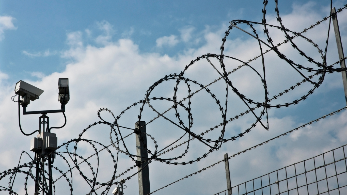 A barbed wire fence with two cameras on top of it