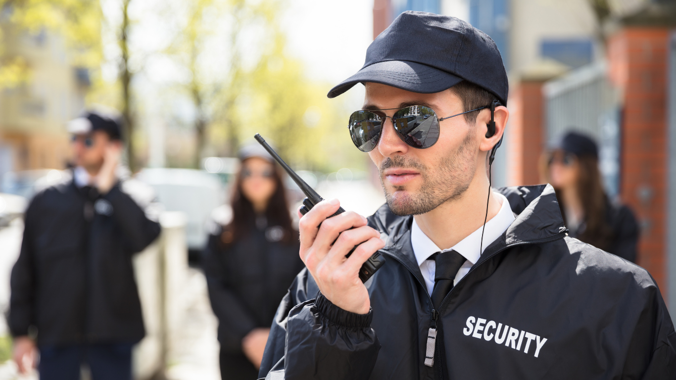 A security guard is talking on a walkie talkie.