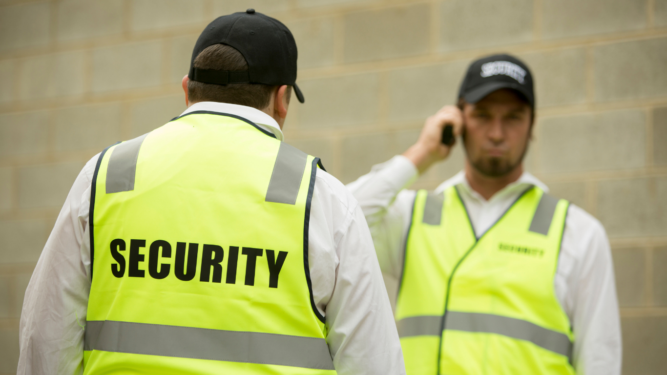 Two security guards are standing next to each other in front of a brick wall