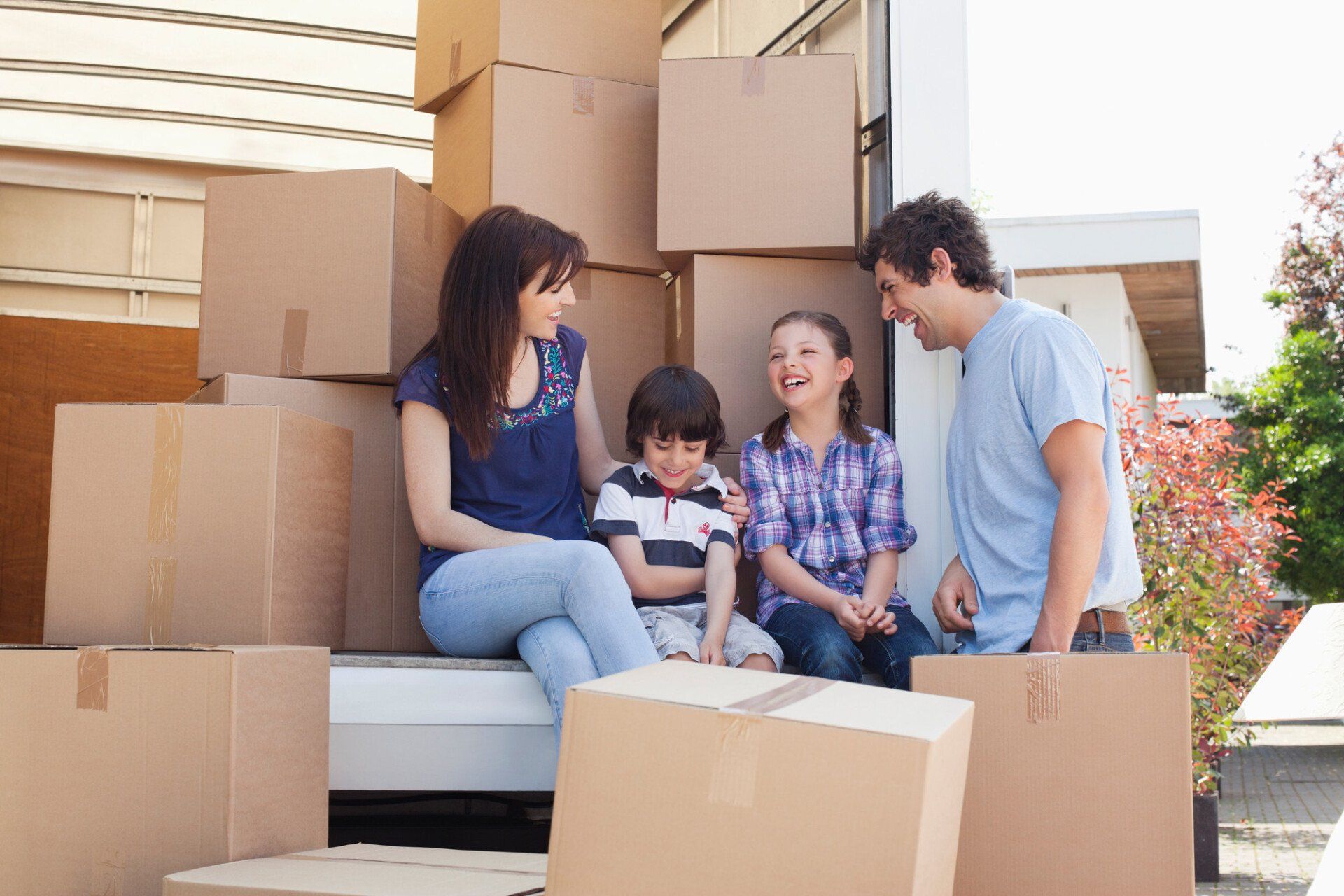 Family sitting on back of moving van