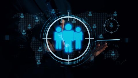 Person in a suit interacting with a digital interface, targeting a group of people icons within a world map.