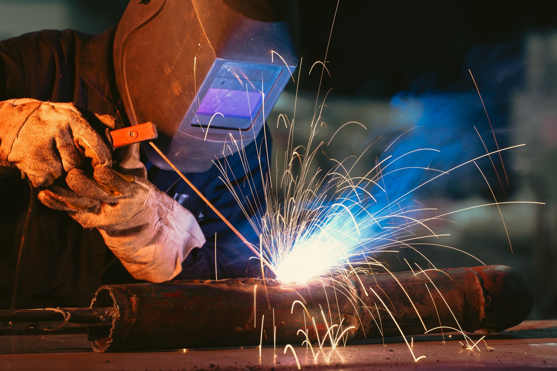 Professional welding services with a welder in protective gear working on a metal pipe.