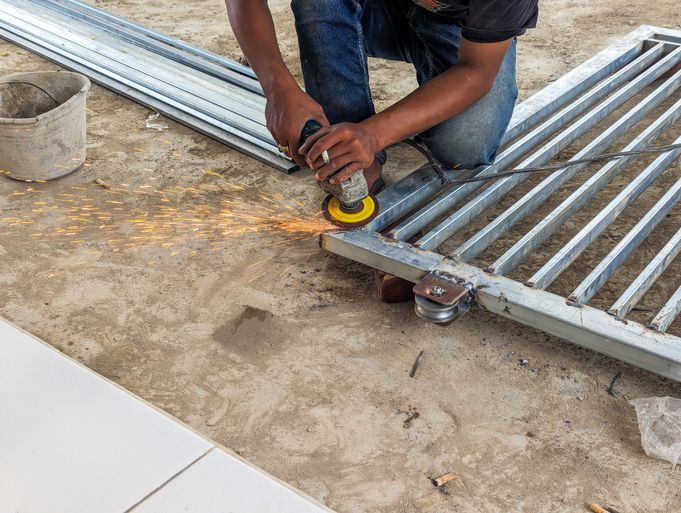 A fence worker is smoothing an iron fence.