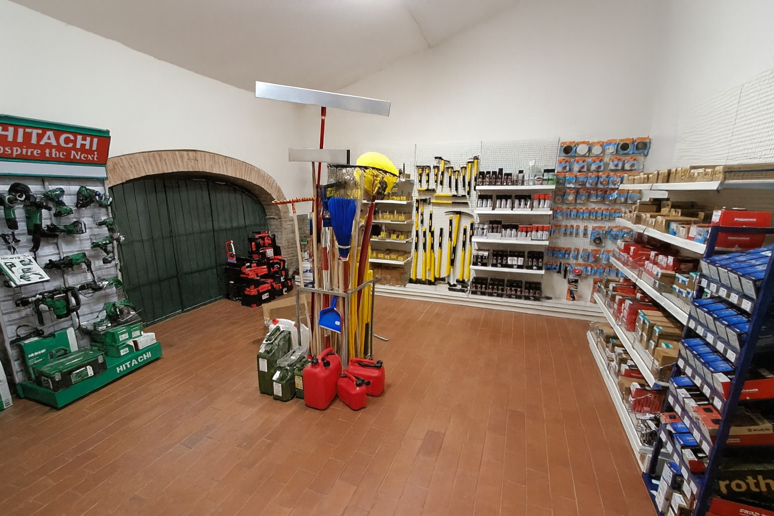 Interno di un negozio di ferramenta con attrezzi esposti su scaffali e rastrelliere, pavimenti in legno.