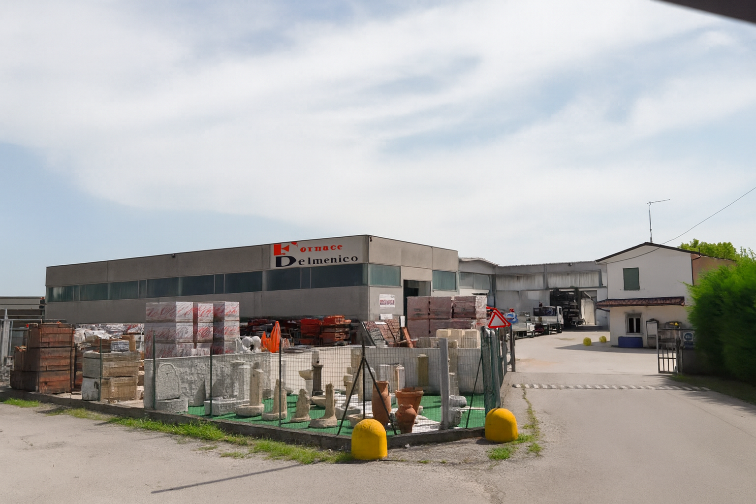 Negozio di materiali edili con materiali accatastati all'esterno, cielo coperto.