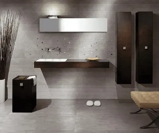 Bagno moderno con pareti grigie, mobiletto in legno scuro, armadietti alti neri e panca.