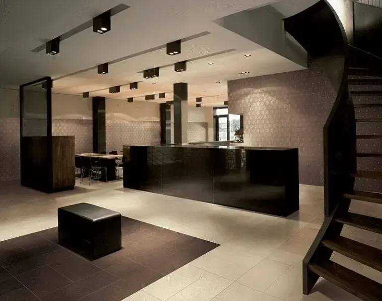 Moderno spazio commerciale con infissi neri, pareti neutre e una scala a chiocciola.