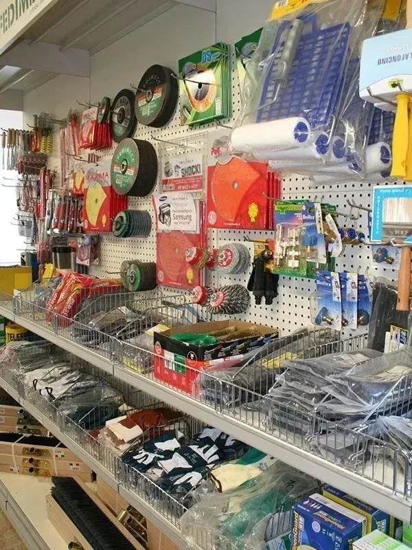 Scaffali pieni di vari utensili e forniture per ferramenta in un ambiente da negozio.