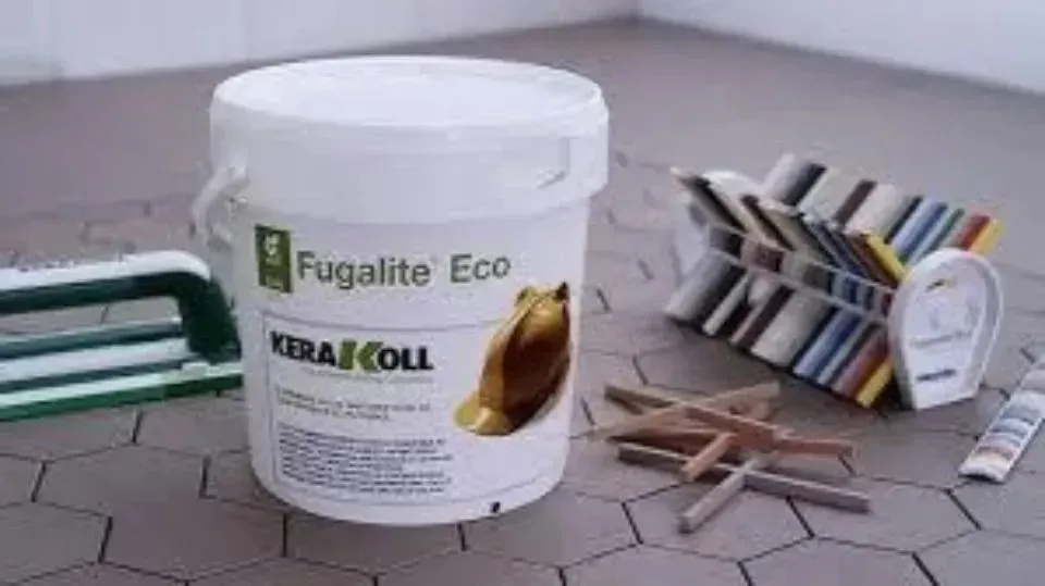 Secchio bianco di stucco Fugalite Eco su pavimento piastrellato, con campioni di colore e strumenti.