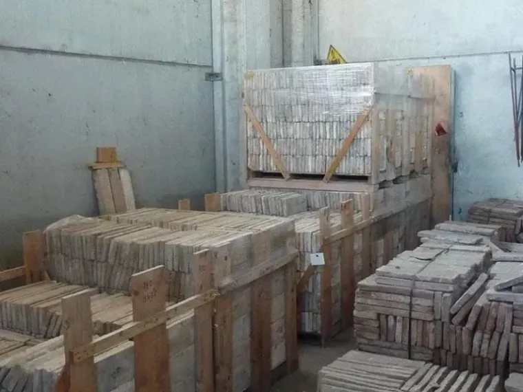 Casse di legno impilate con piastrelle rettangolari all'interno di un magazzino.