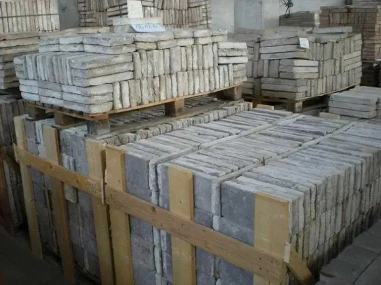 Pallet accatastati con piastrelle di pietra rettangolari all'interno di un magazzino.