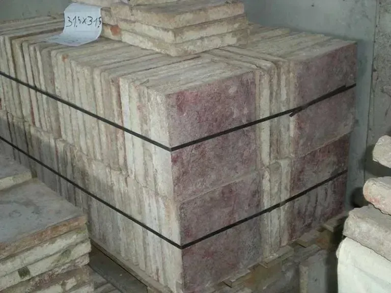 Pila di mattoni color marrone-rossastro e beige, legati con cinghie nere e con un'etichetta di carta in cima.