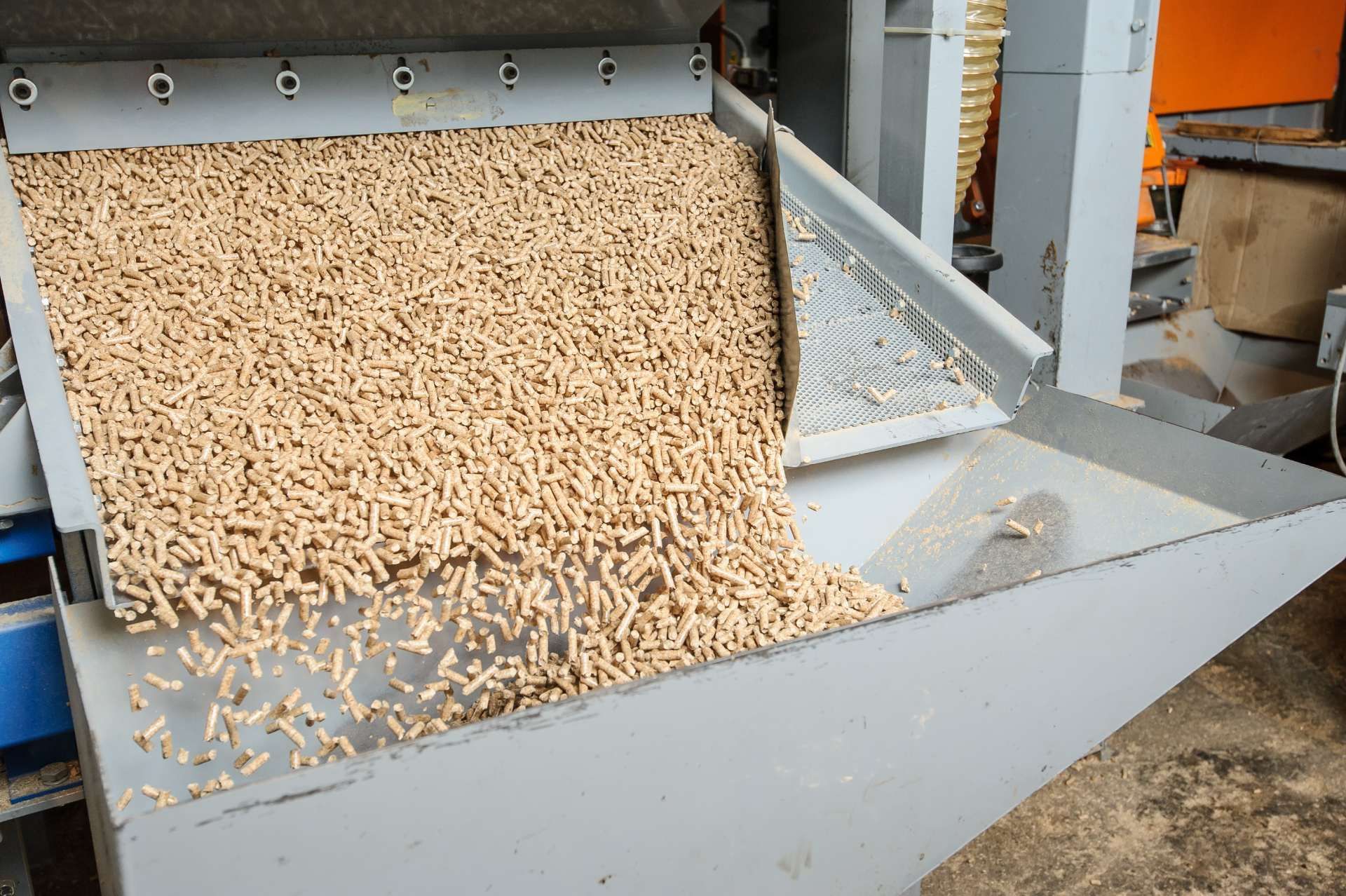 Pellet di legno che vengono versati da una macchina in un contenitore di metallo.