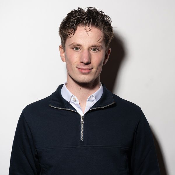 Een jongeman in een zwarte trui en een wit overhemd