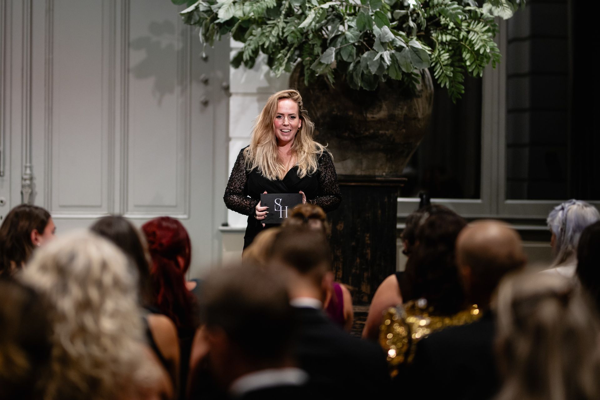 Een vrouw staat voor een groep mensen.