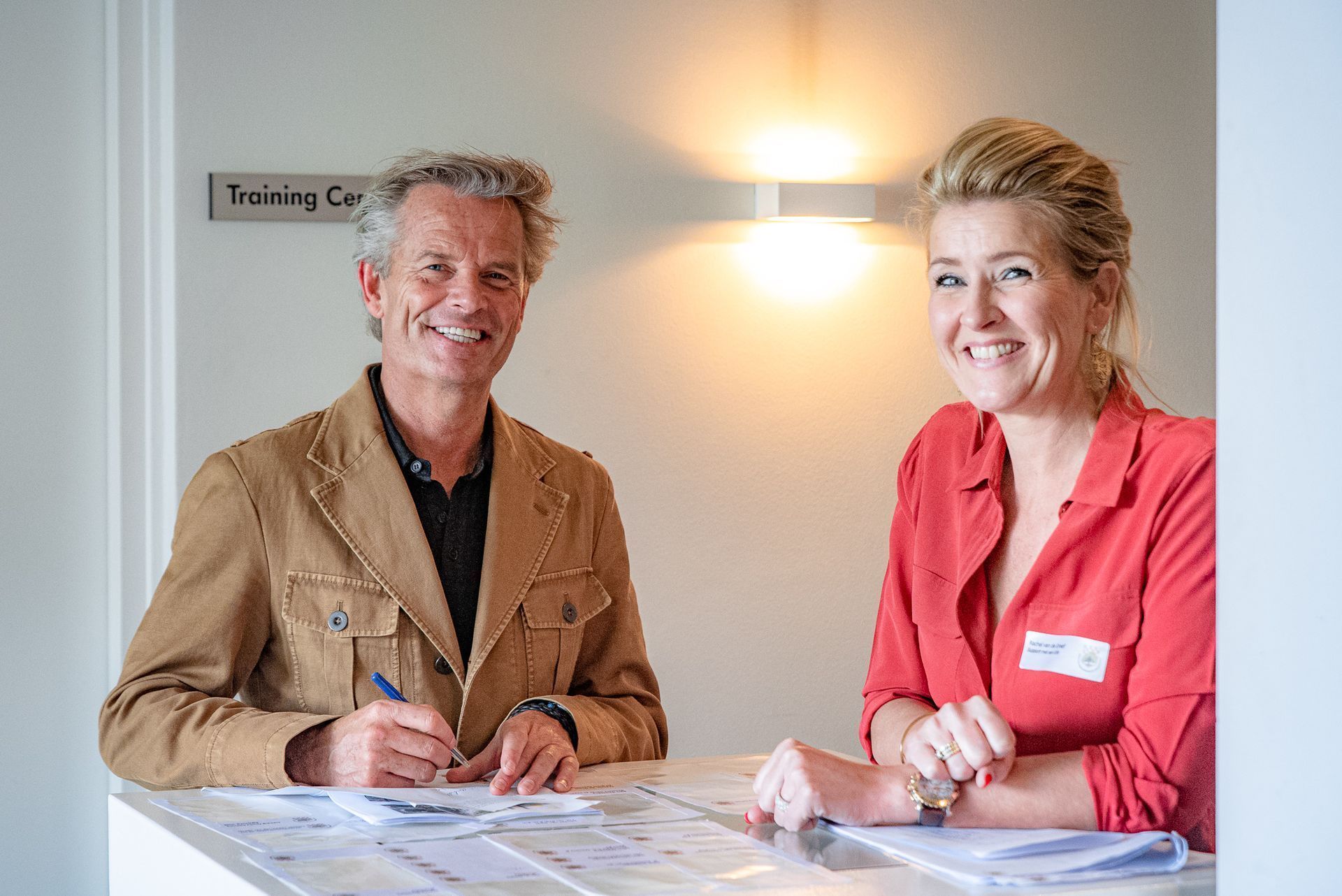Een man en een vrouw zitten aan een tafel en lachen.