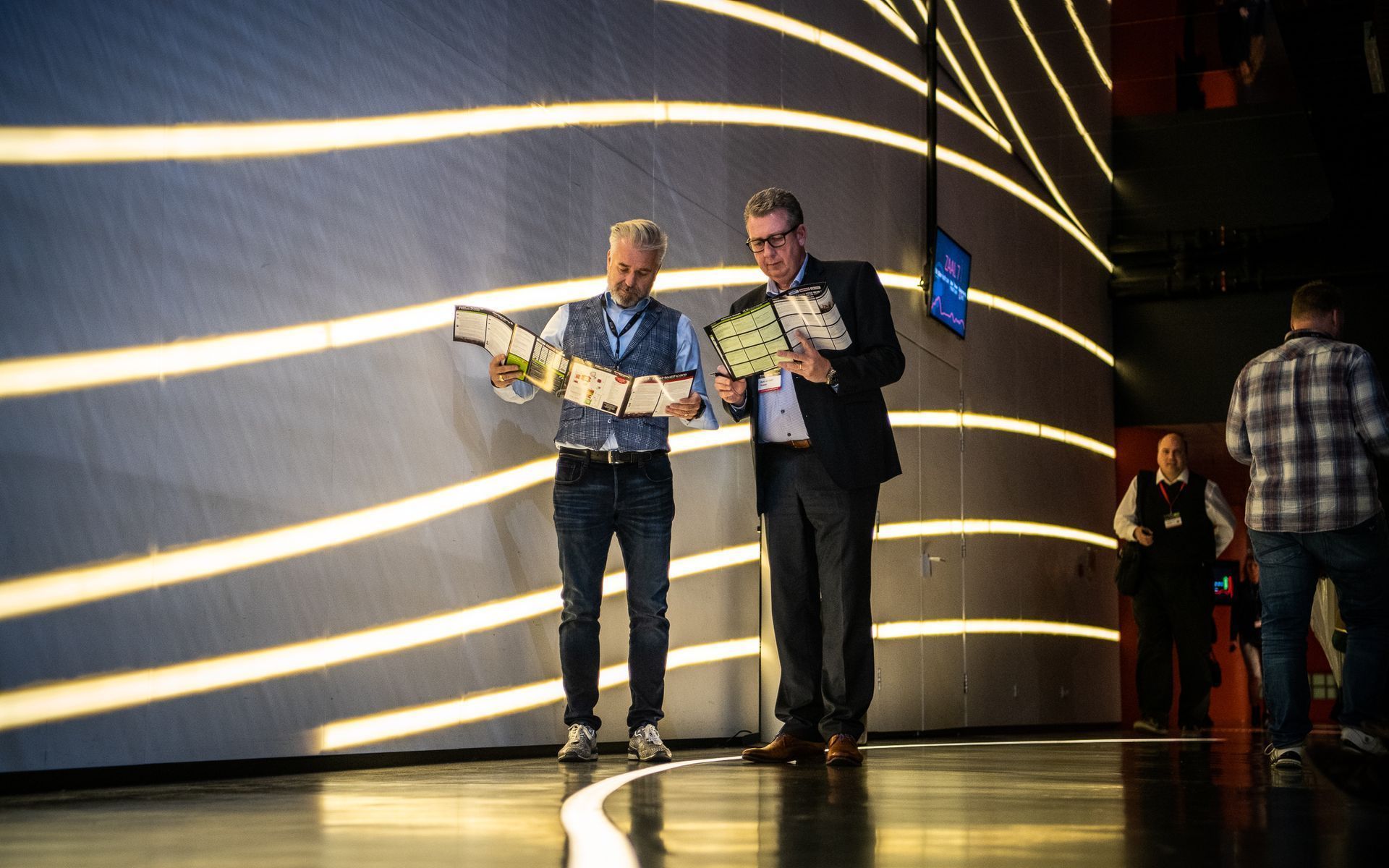 Twee mannen staan op een podium en kijken naar een stuk papier.