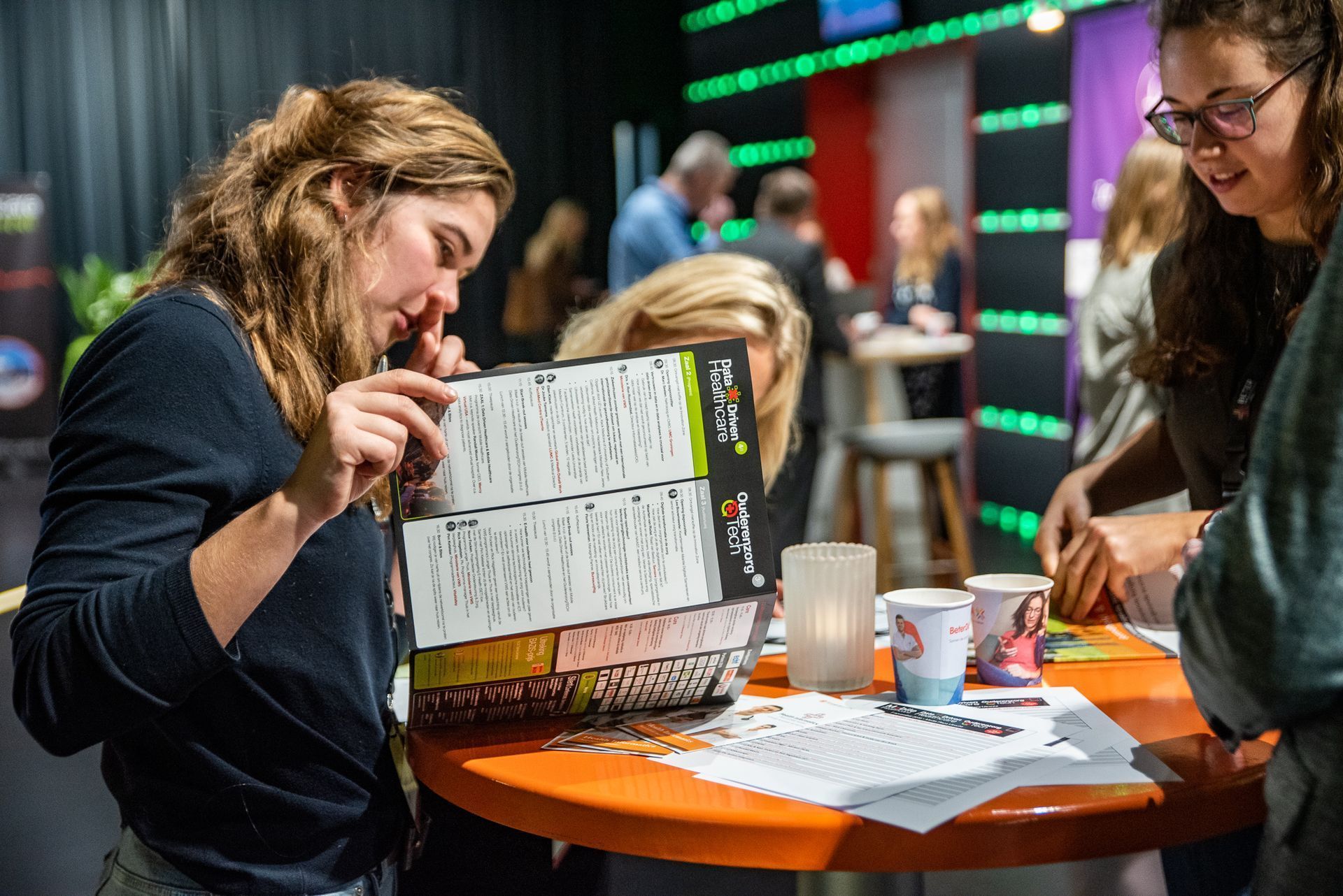 Een groep vrouwen zit aan een tafel en kijkt naar een doos.